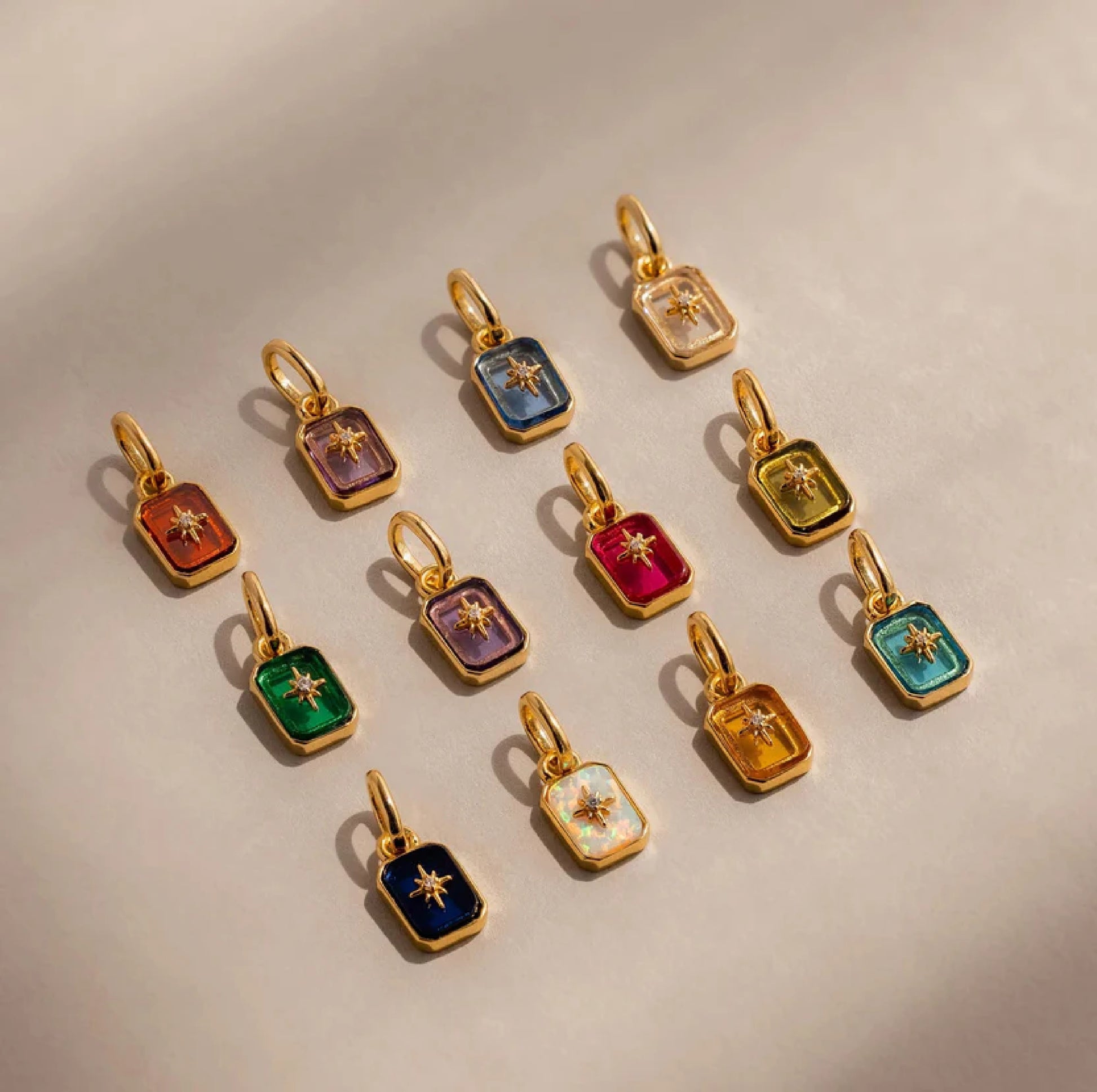 Gold pendants with colorful gemstones on a beige background