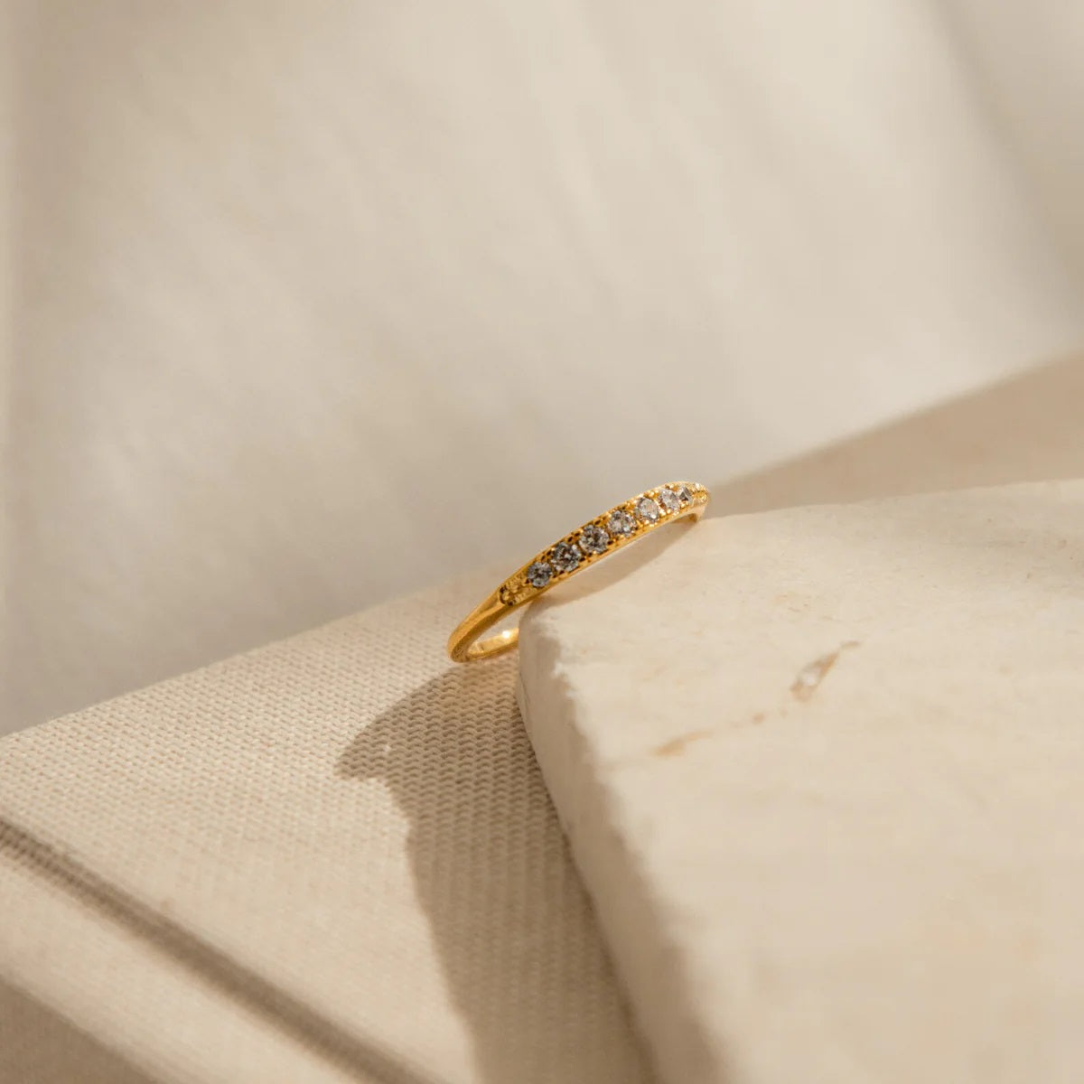 Gold ring with small diamonds on a beige fabric background