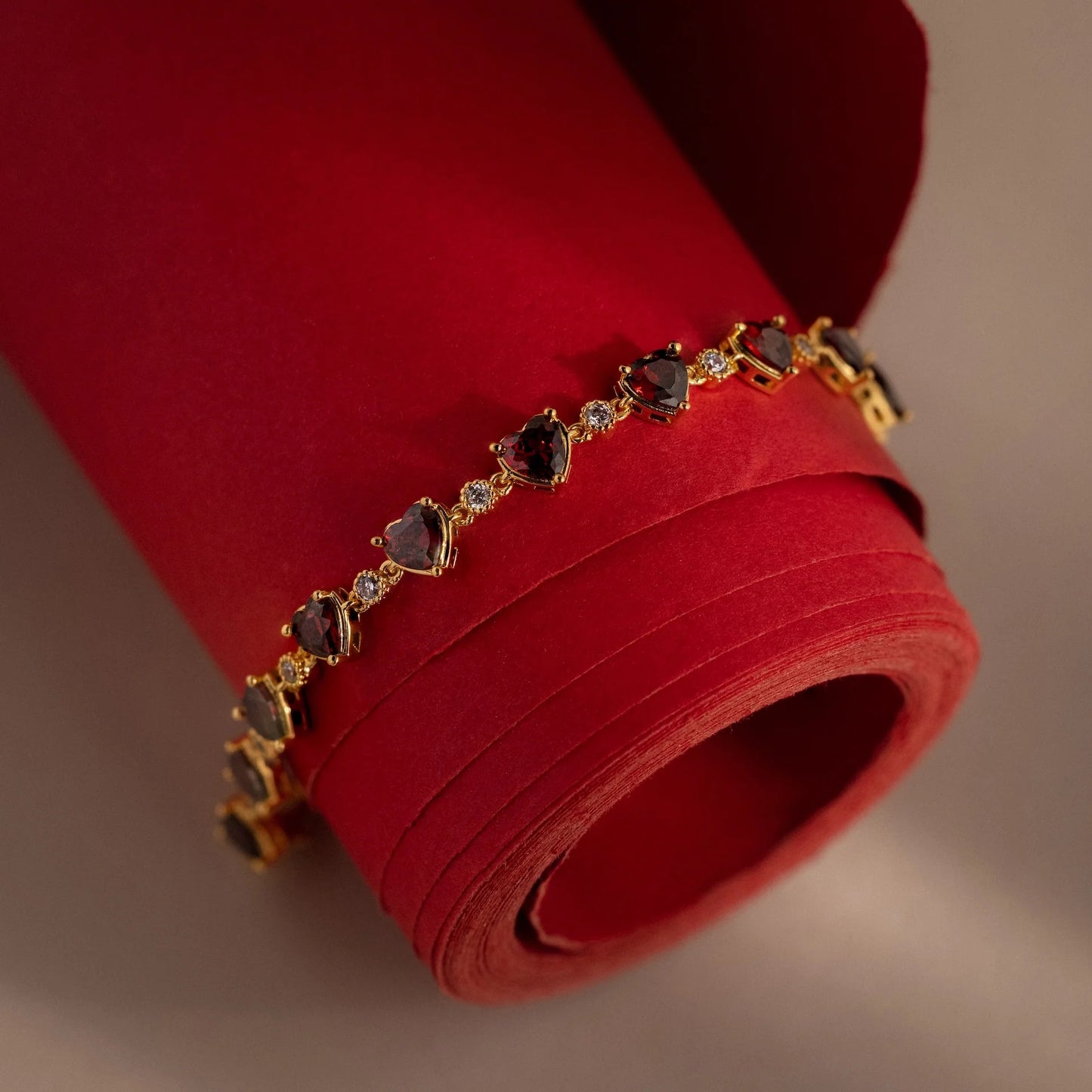 Gold bracelet with gemstones on a red fabric background