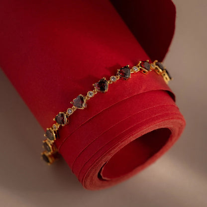 Gold bracelet with gemstones on a red fabric background