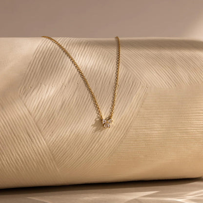 Gold necklace on a textured beige surface