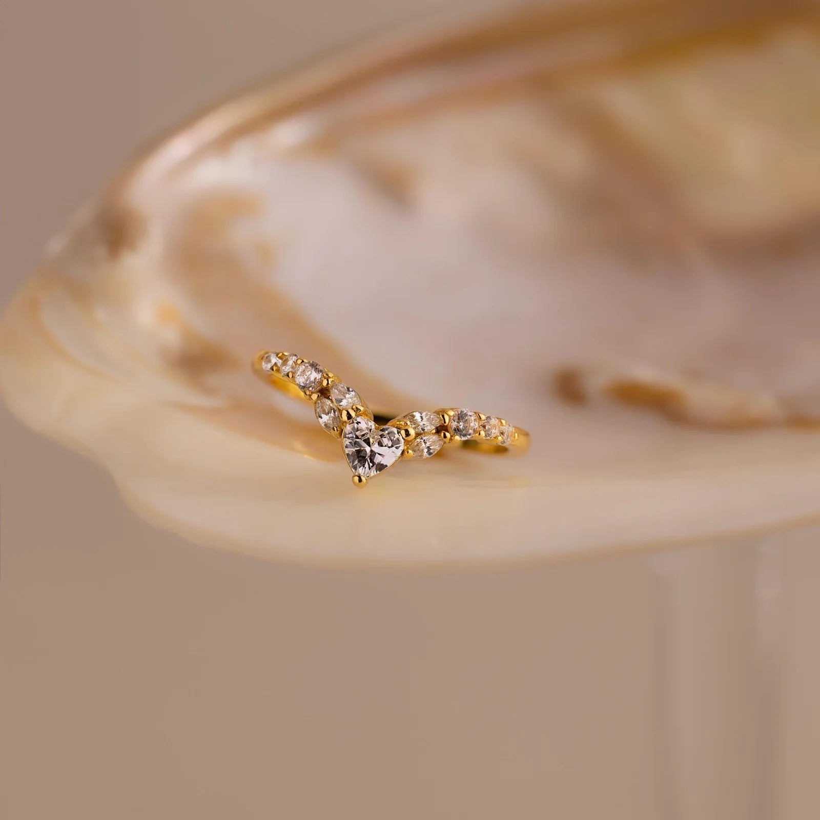 Gold ring with small diamonds on a beige shell background