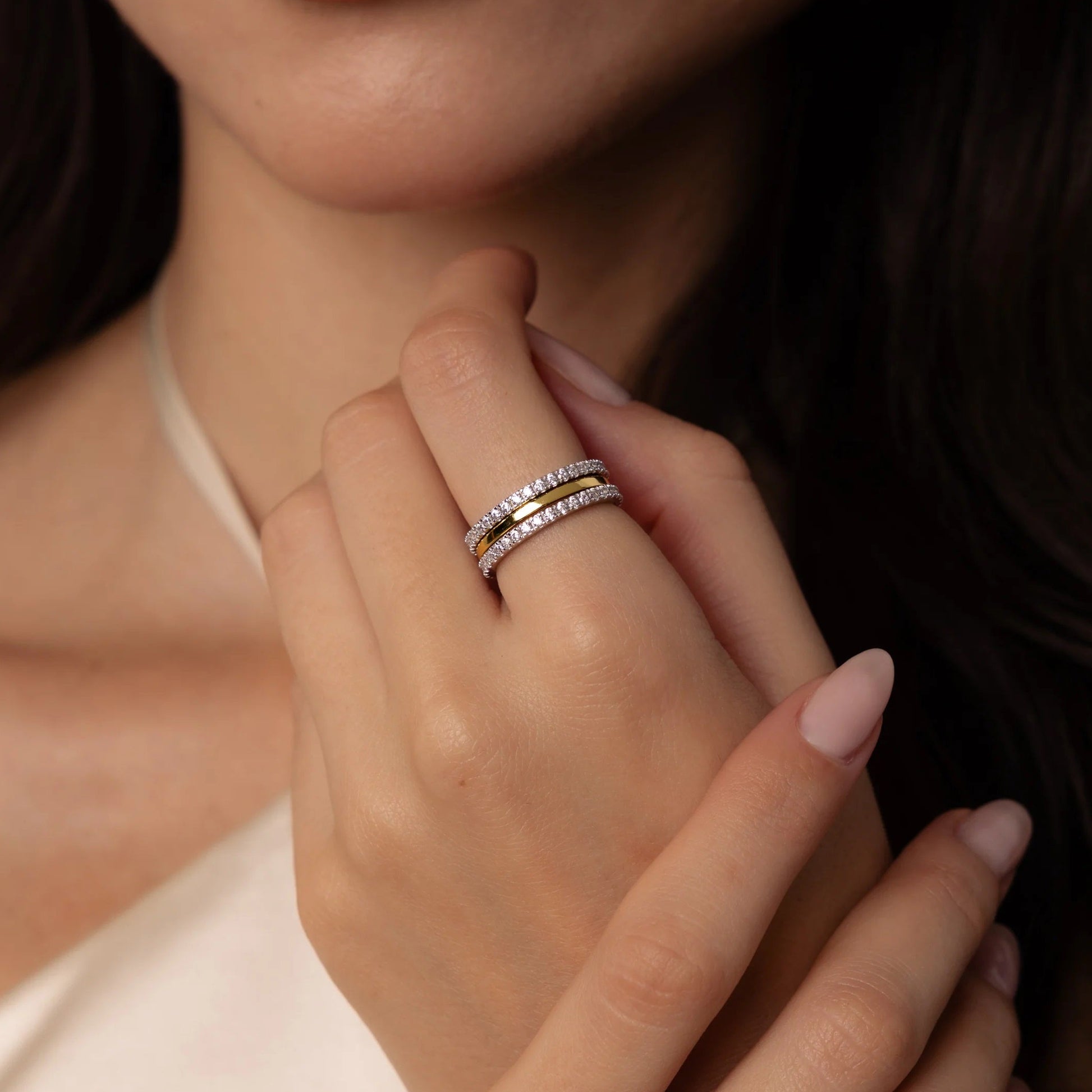 Close-up of a woman's hand wearing two rings with a neutral background