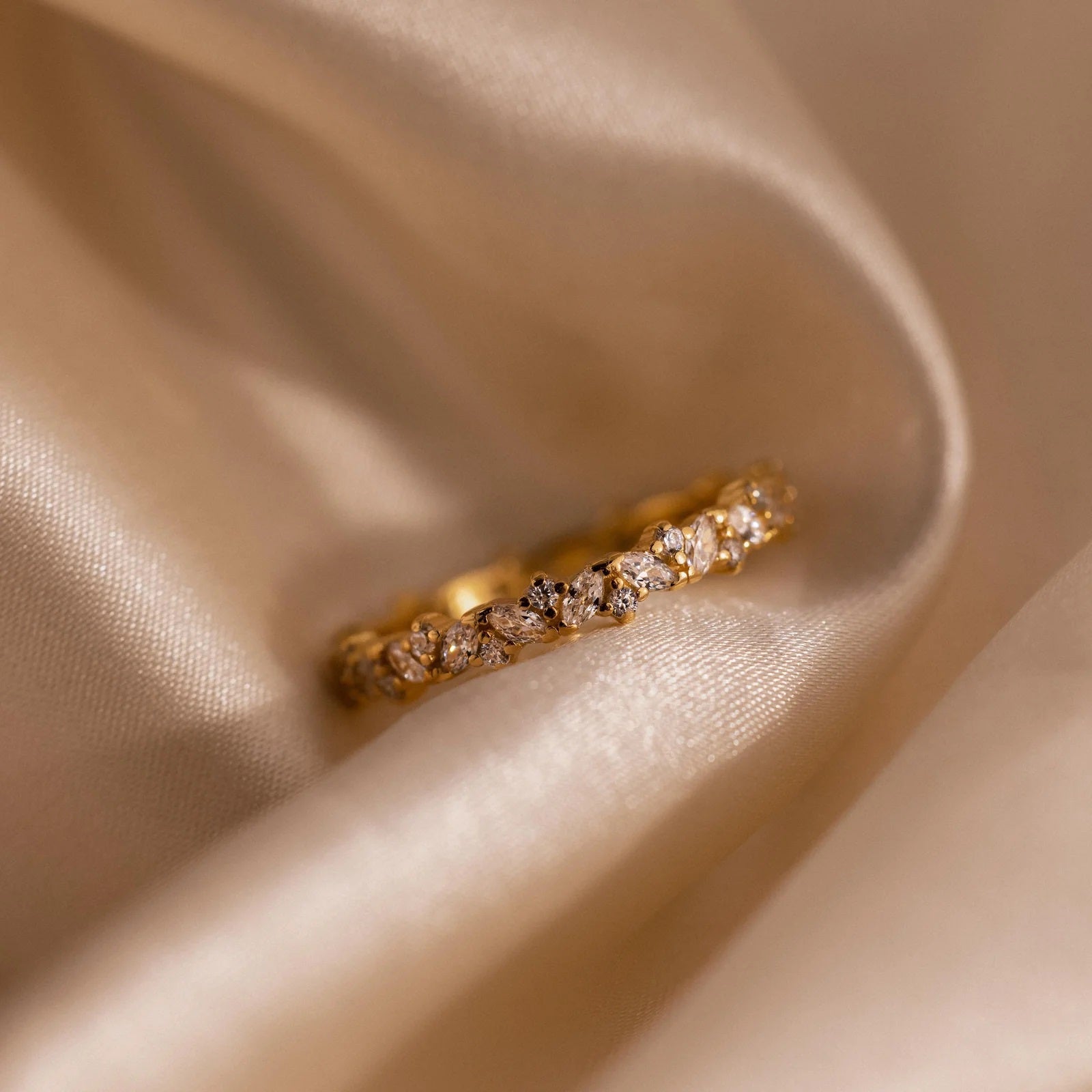 Gold ring with diamonds on a beige fabric background