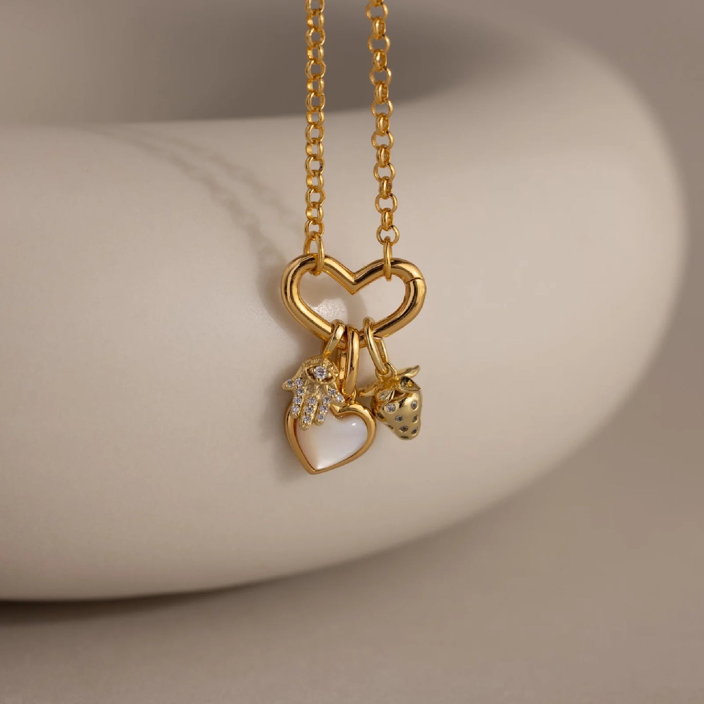 Gold necklace with heart-shaped pendants on a neutral background