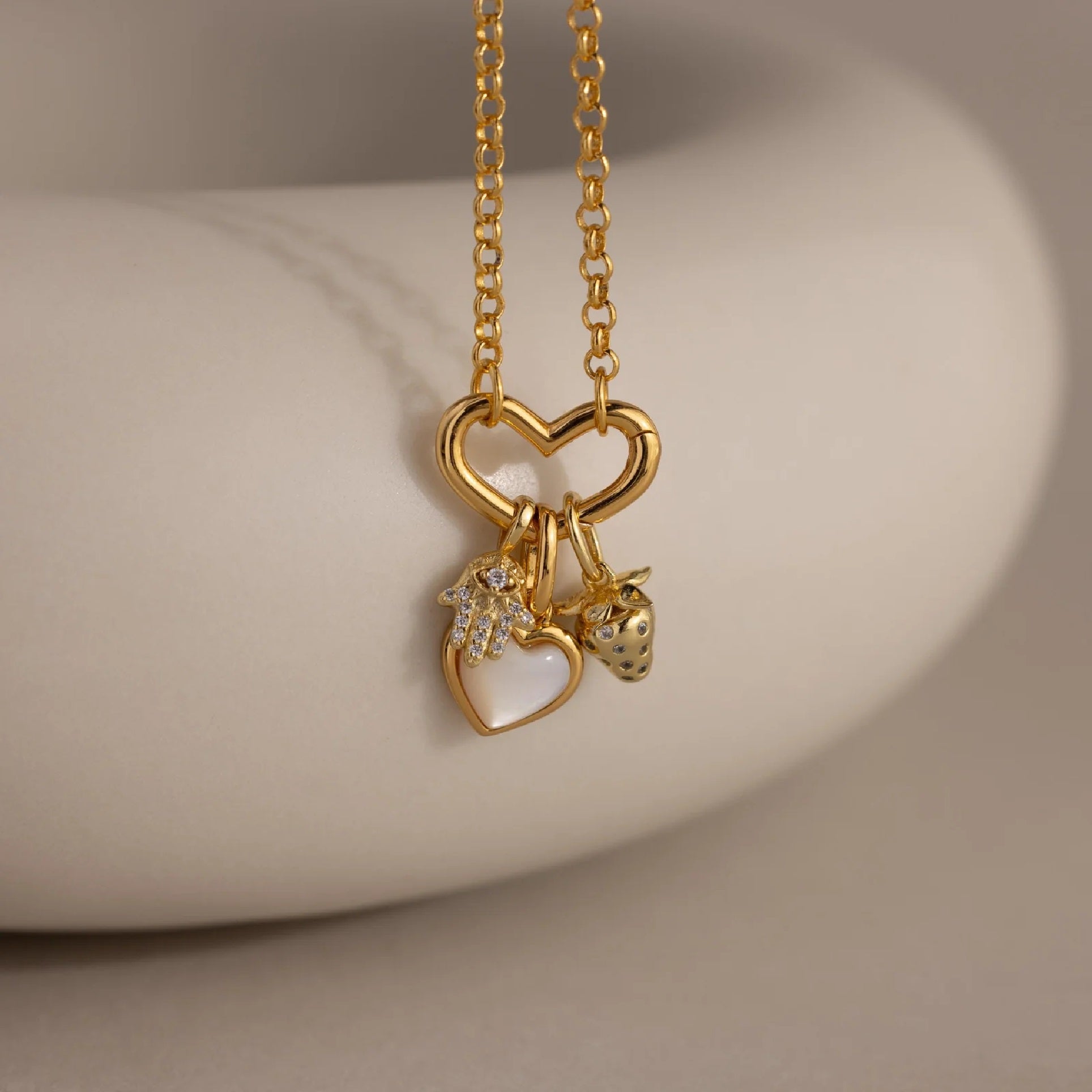 Gold necklace with heart-shaped pendants on a neutral background