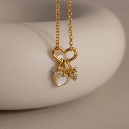 Gold necklace with heart-shaped pendants on a neutral background