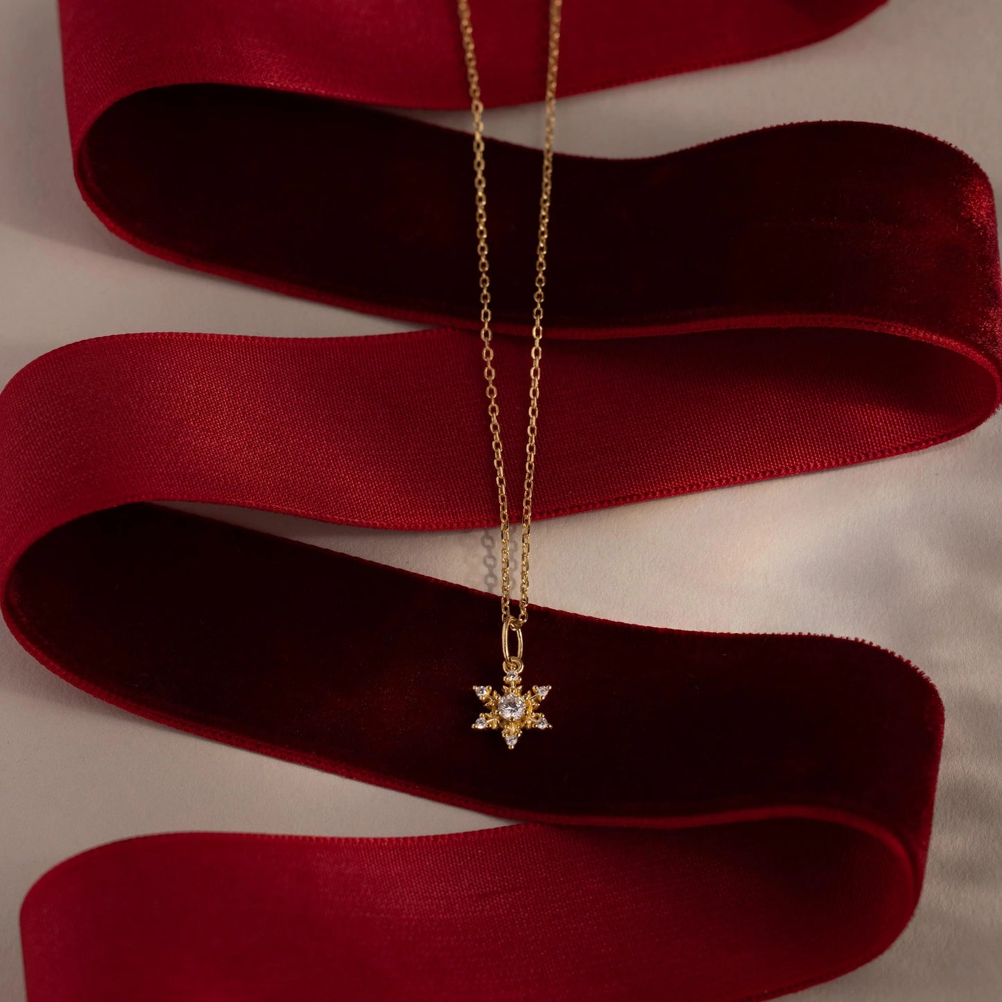 Gold necklace with a star-shaped pendant on a red ribbon