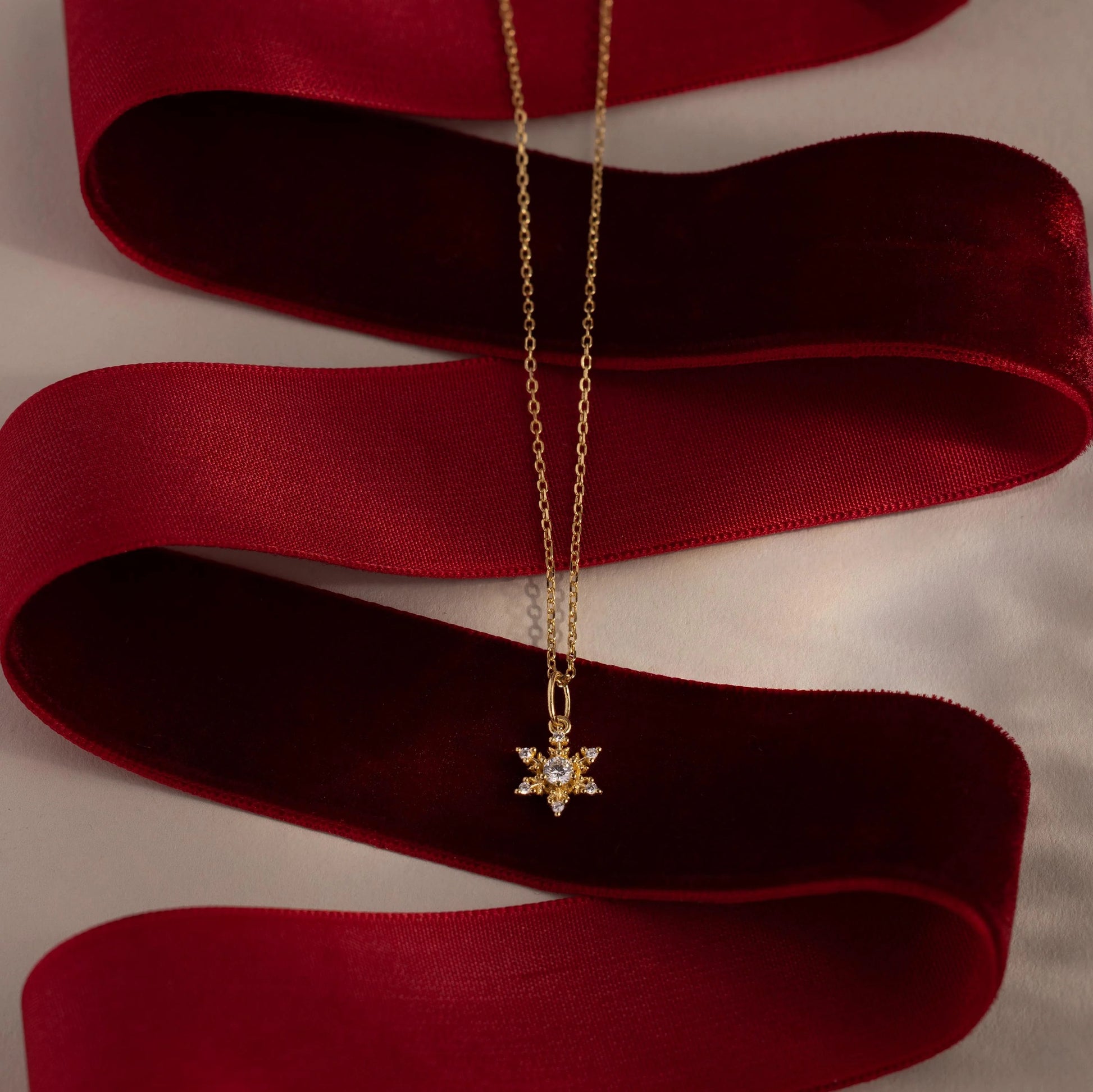 Gold necklace with a star-shaped pendant on a red ribbon
