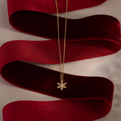 Gold necklace with a star-shaped pendant on a red ribbon