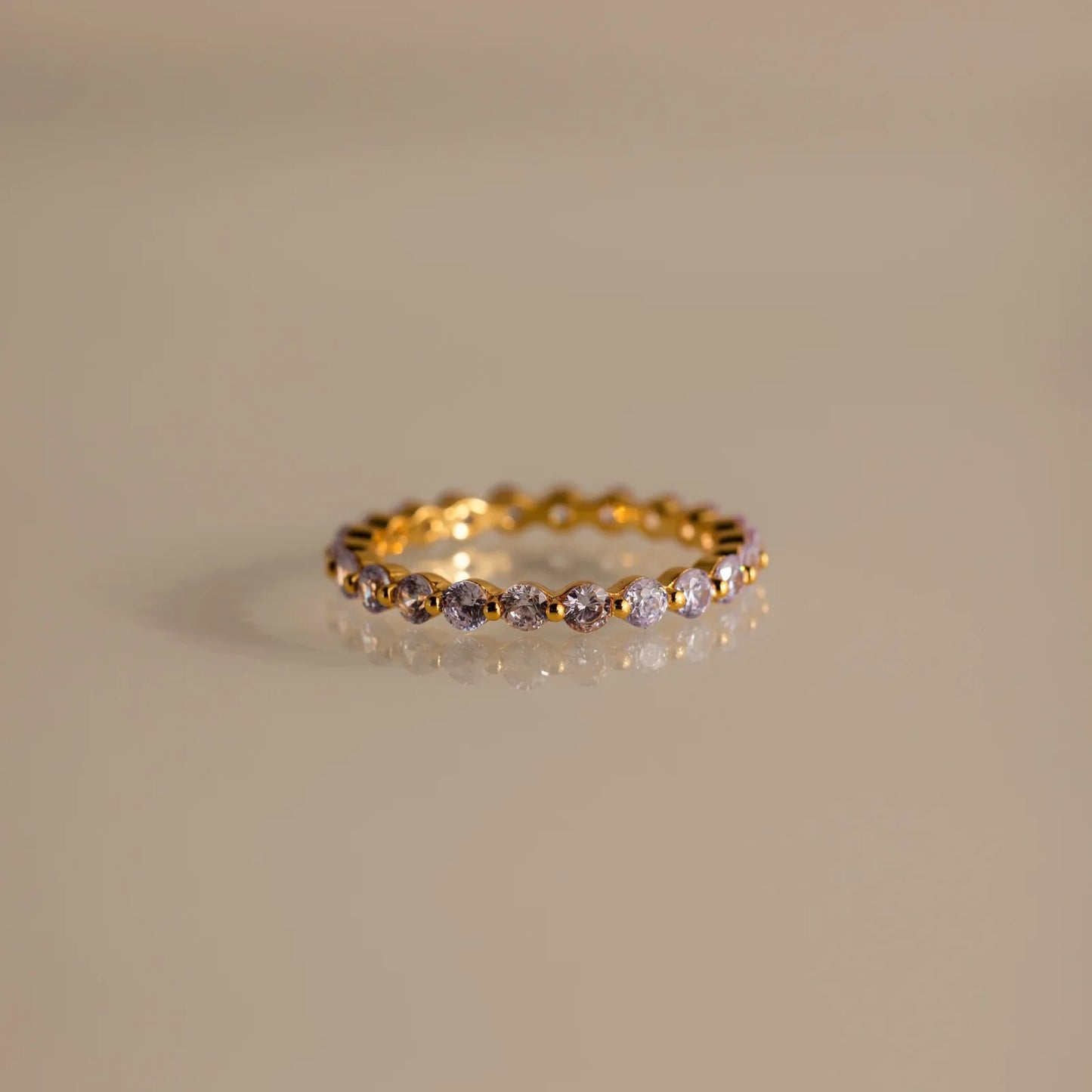 Gold ring with embedded diamonds on a beige background