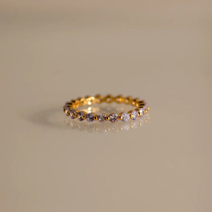 Gold ring with embedded diamonds on a beige background