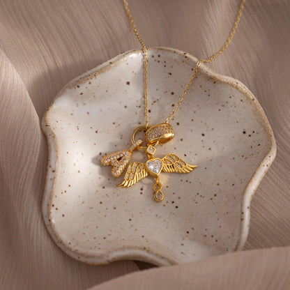 Gold necklace with heart and wing pendant on a ceramic dish