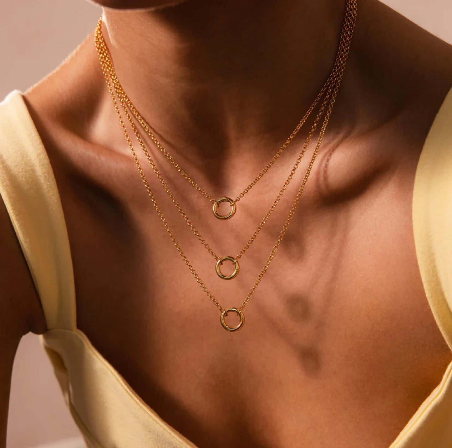 Close-up of a person wearing a gold necklace with circular pendants.