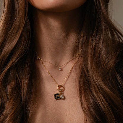 Close-up of a woman wearing a delicate gold necklace with a pendant.
