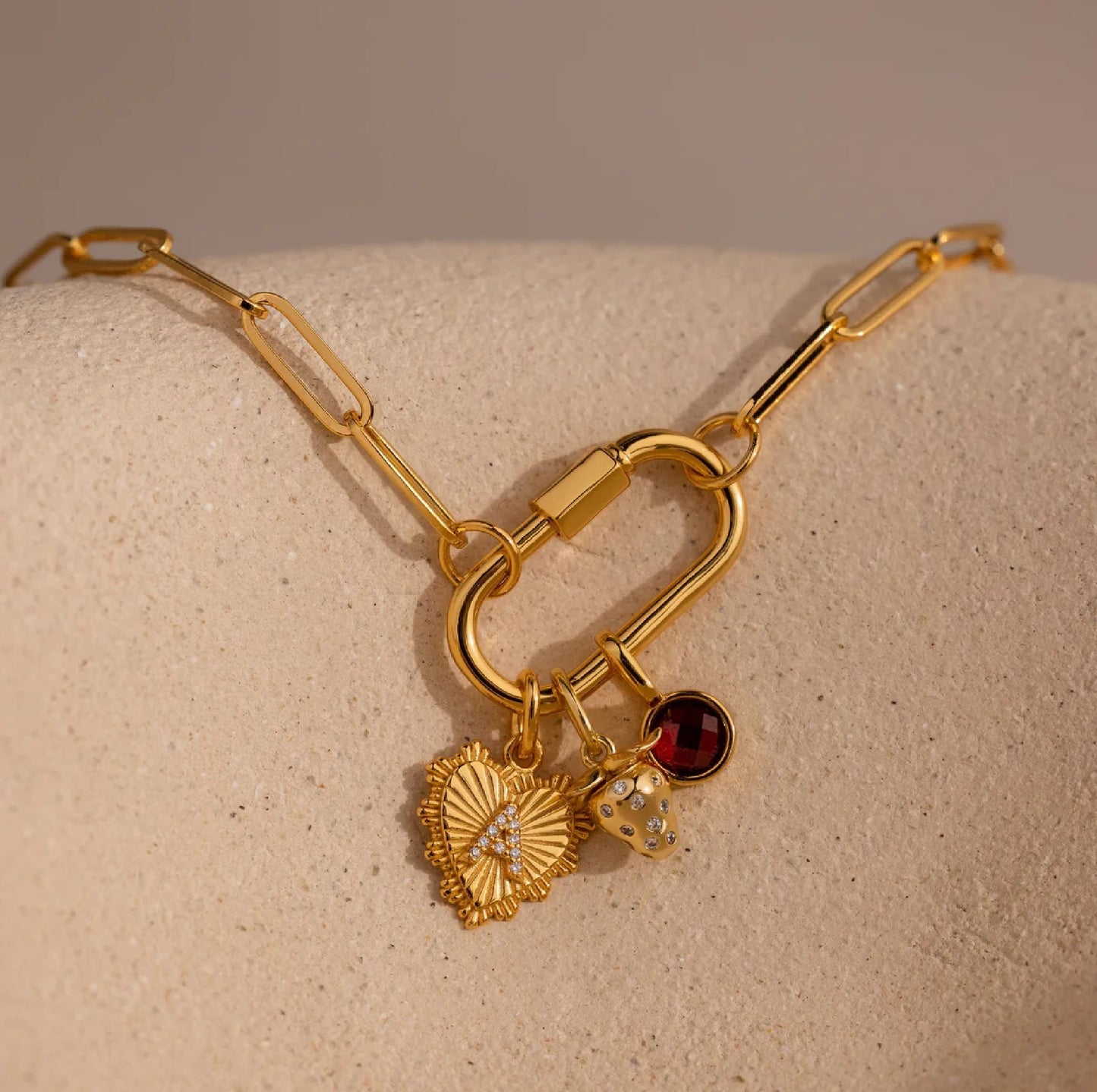 Gold necklace with charms on a beige surface