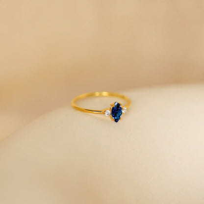 Gold ring with a blue gemstone on a beige background