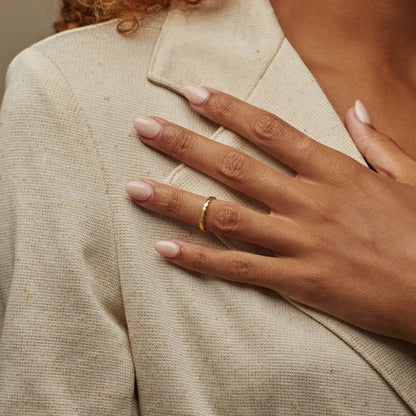 Hand with a gold ring on beige fabric
