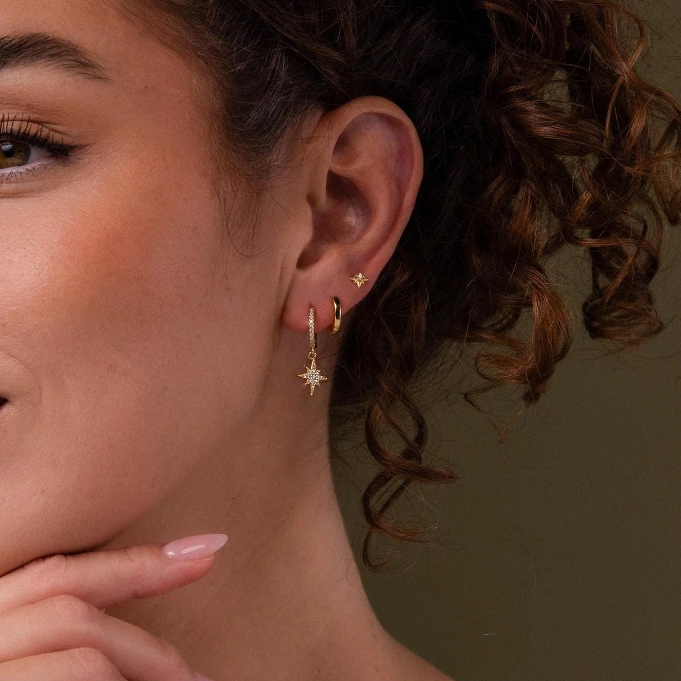 Woman wearing gold earrings with a neutral background
