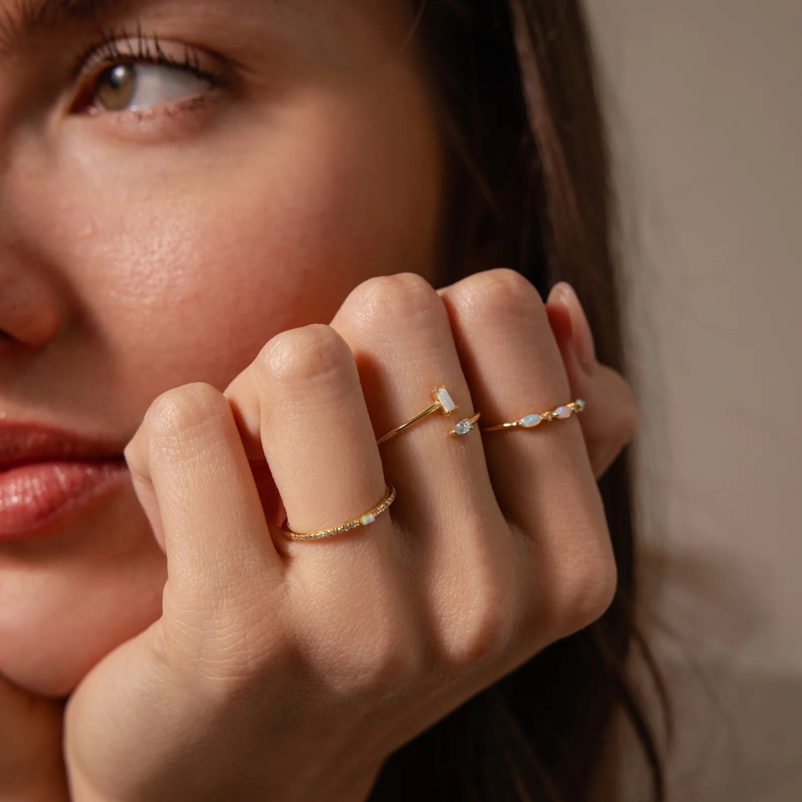 Close-up of a woman's hand wearing multiple gold rings with small diamonds.