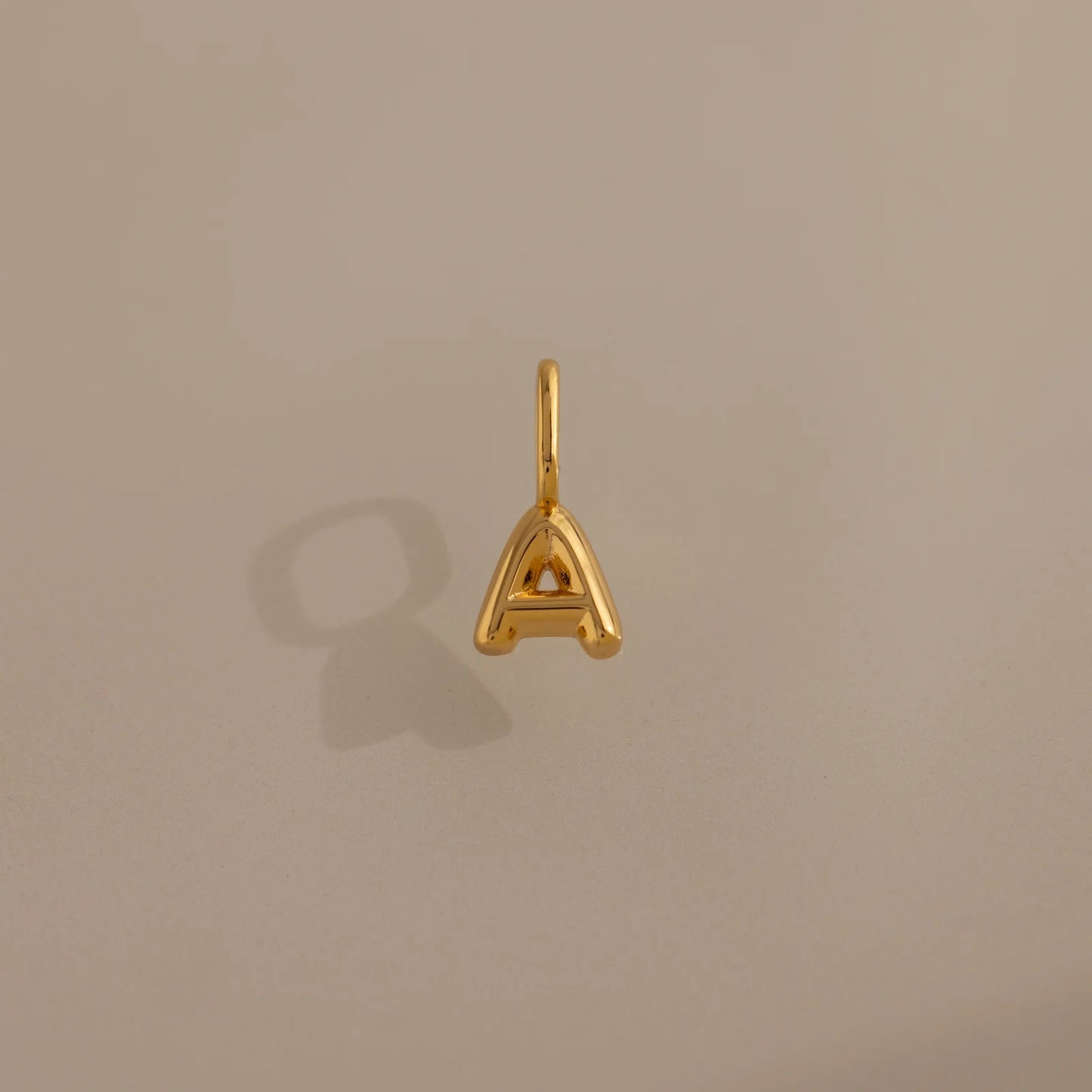 Gold letter 'A' pendant on a beige background