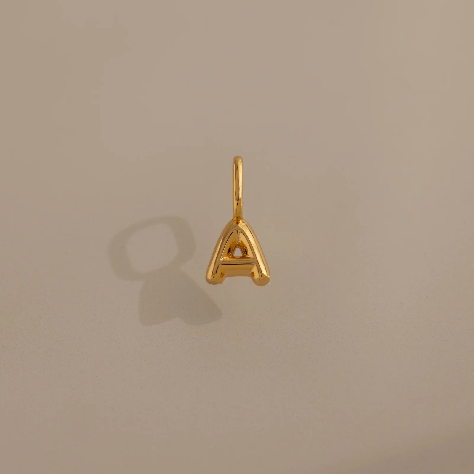 Gold letter 'A' pendant on a beige background