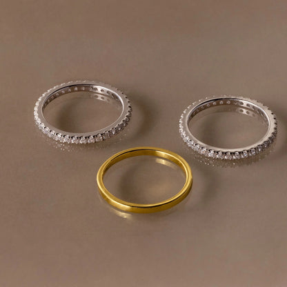 Three rings, two silver and one gold, on a brown background