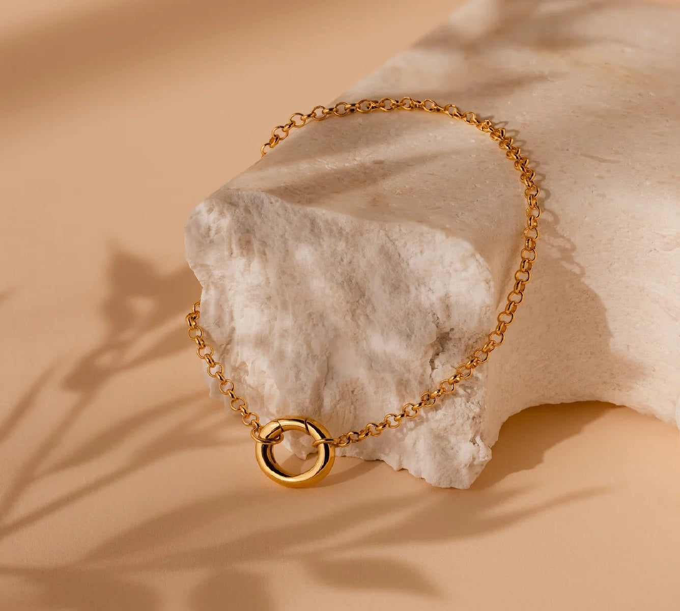 Gold chain bracelet on a textured beige surface
