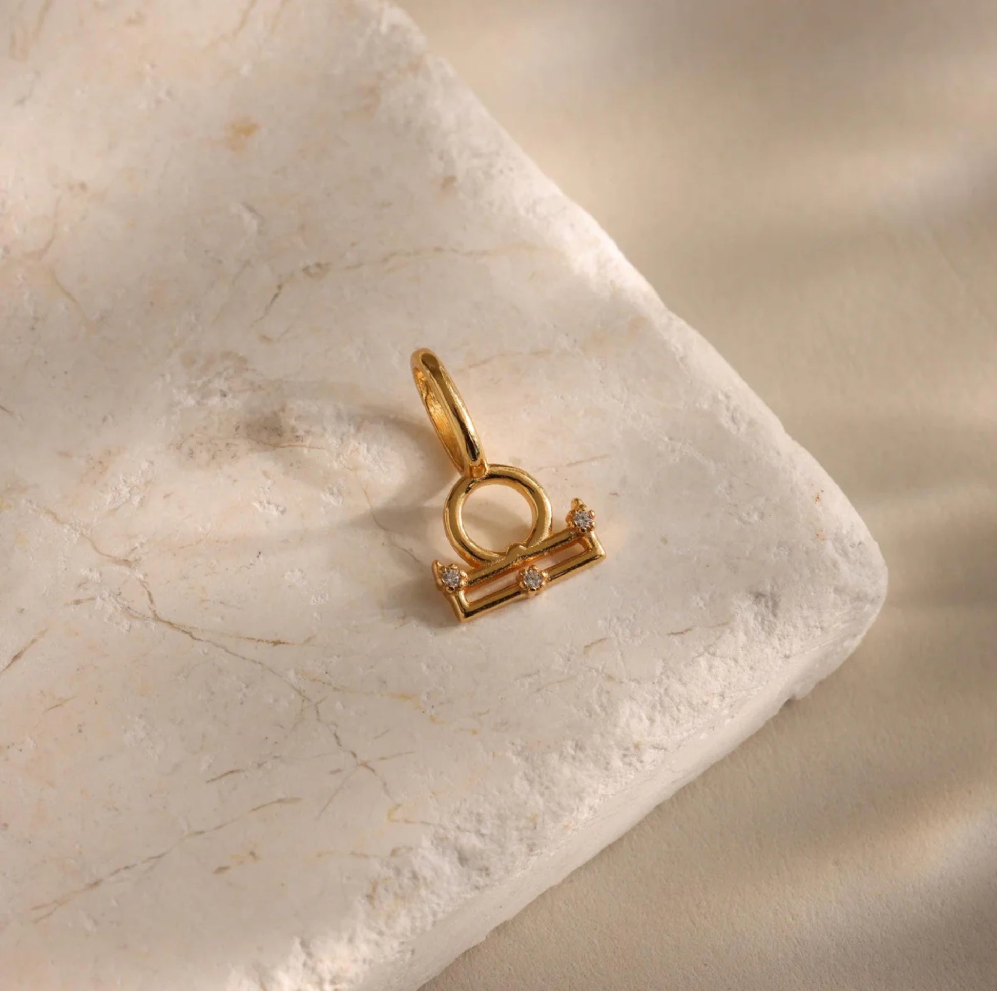 Gold Libra zodiac pendant on a marble surface