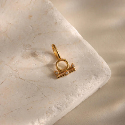 Gold Libra zodiac pendant on a marble surface