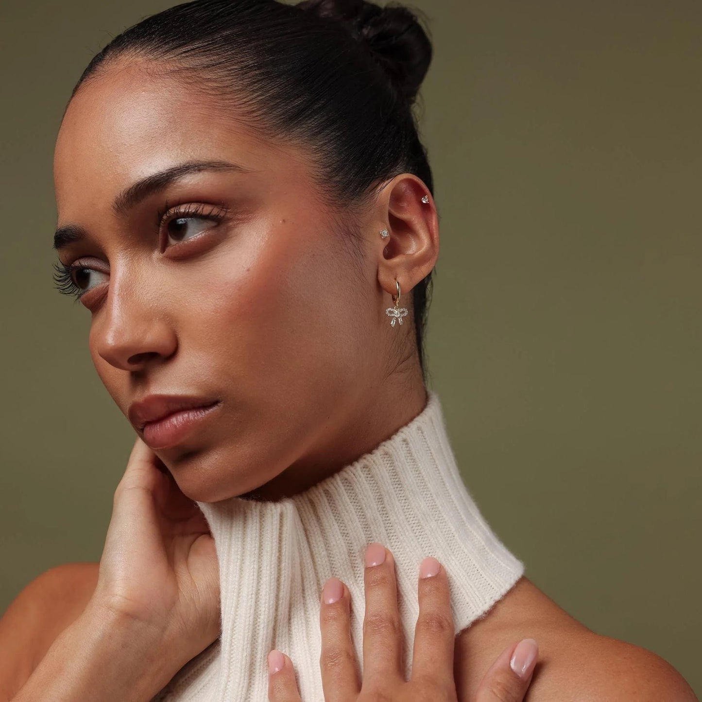 Woman wearing a white turtleneck sweater against a brown background