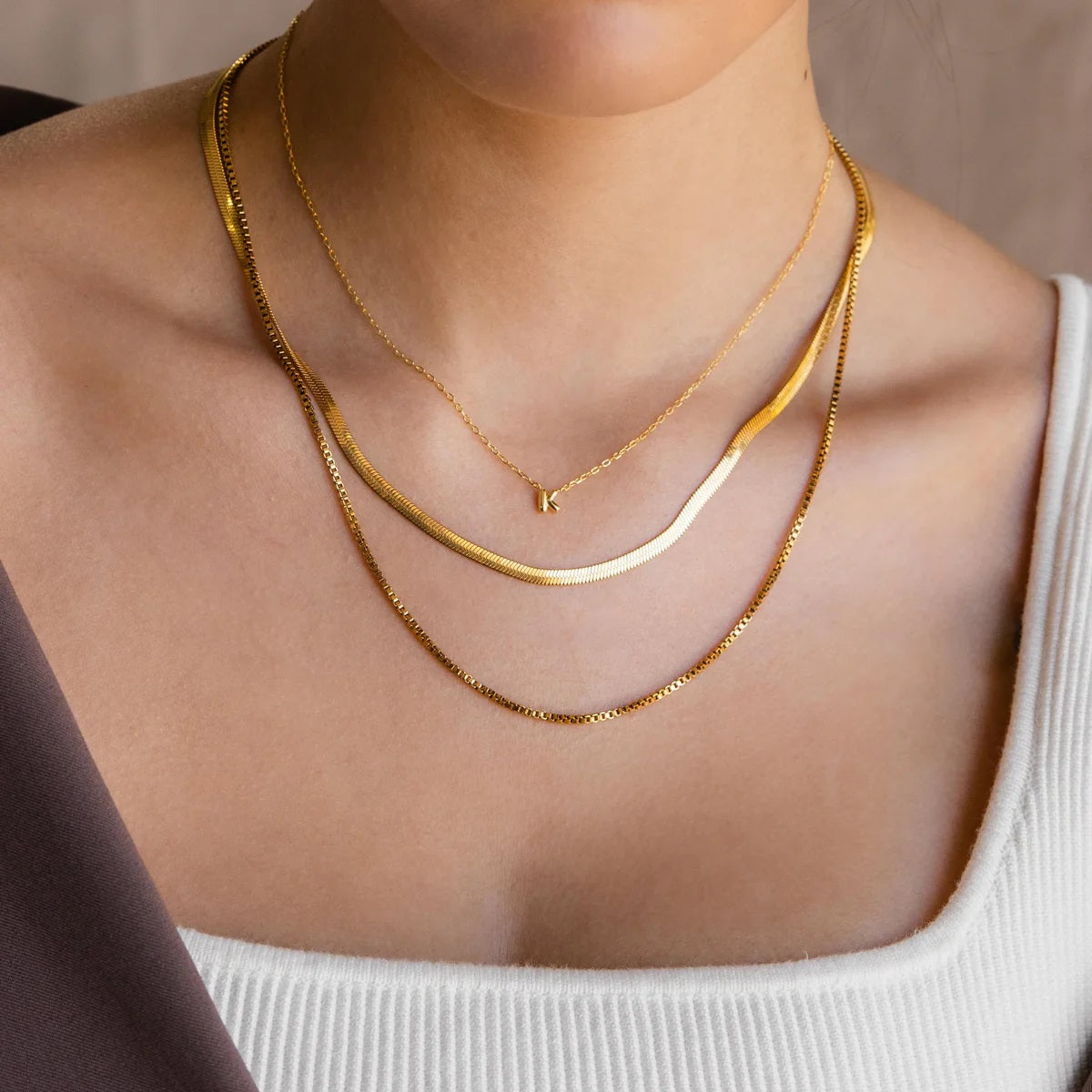 Gold necklaces on a person wearing a white top