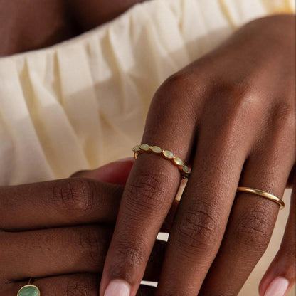 Close-up of a hand wearing gold rings on a neutral background