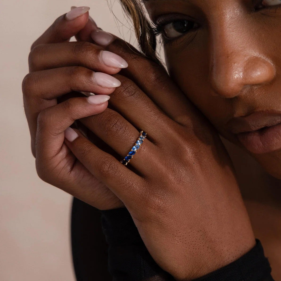 Close-up of a woman with a ring on her finger against a neutral background