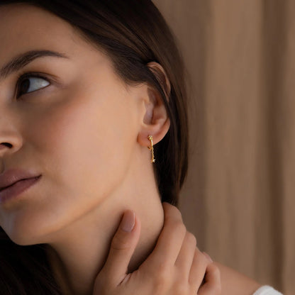 Close-up of a woman wearing a gold earring with a blurred background