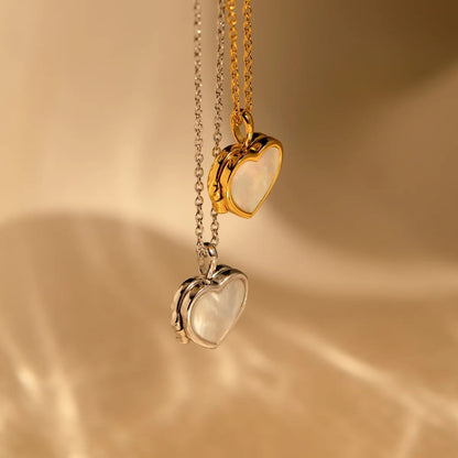 Two heart-shaped pendants on gold and silver chains against a beige background