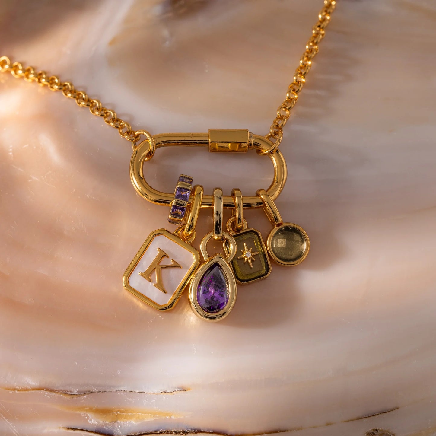 Gold necklace with various charms on a shell background