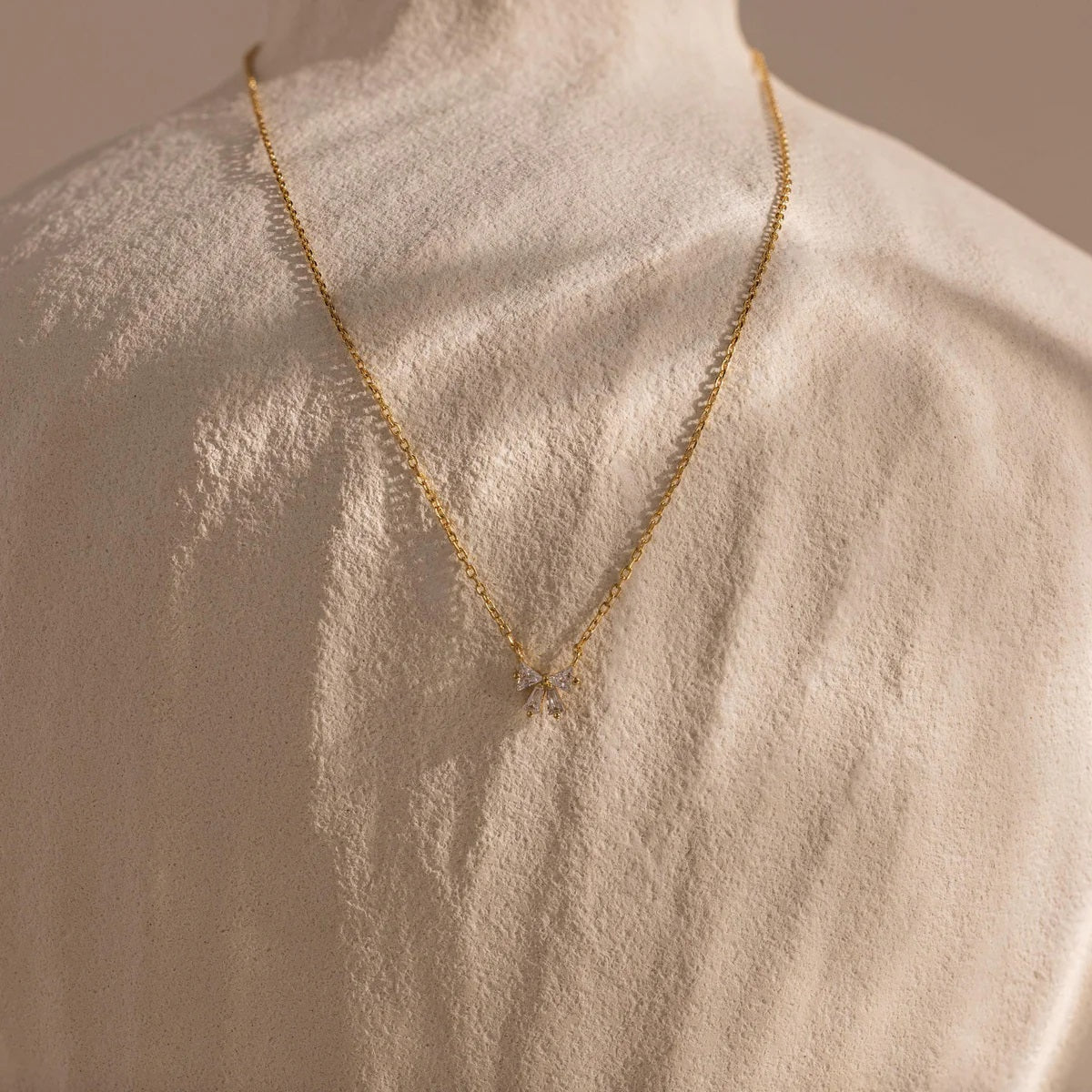 Gold necklace on a mannequin with a neutral background