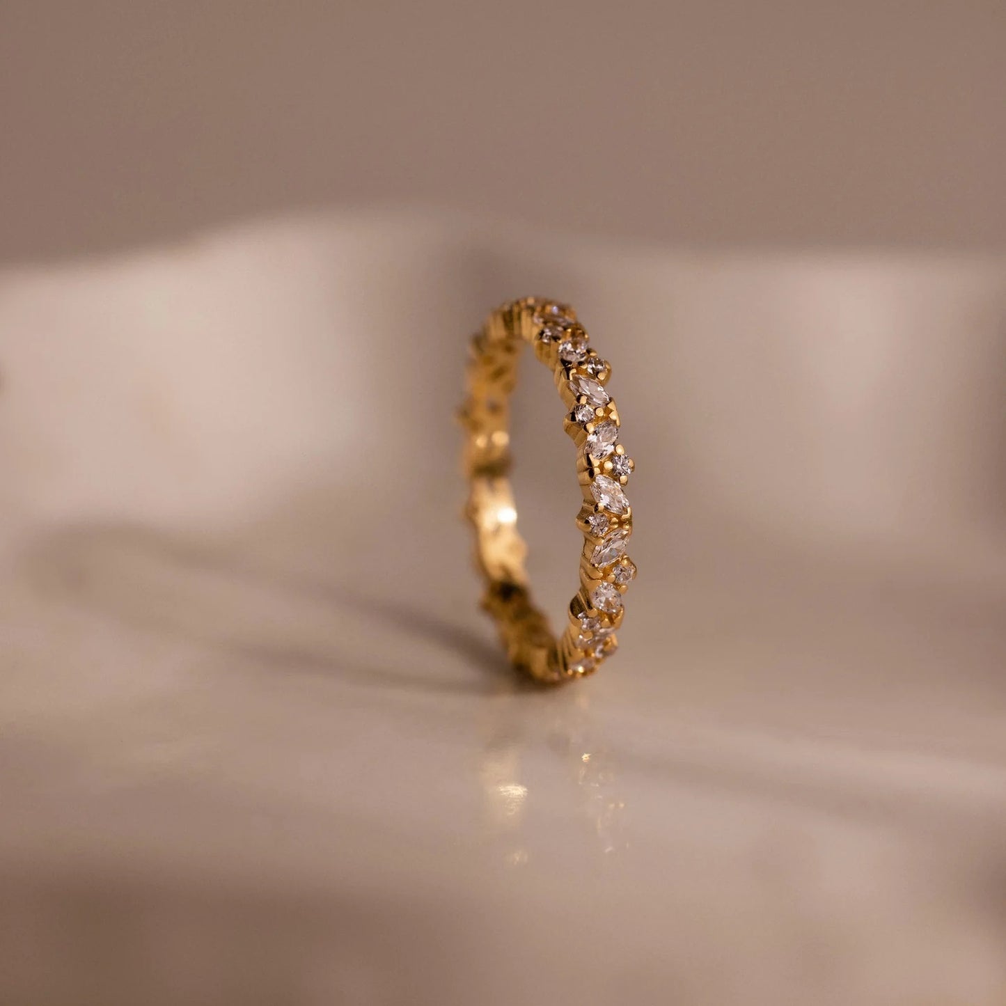 Gold ring with small diamonds on a beige background