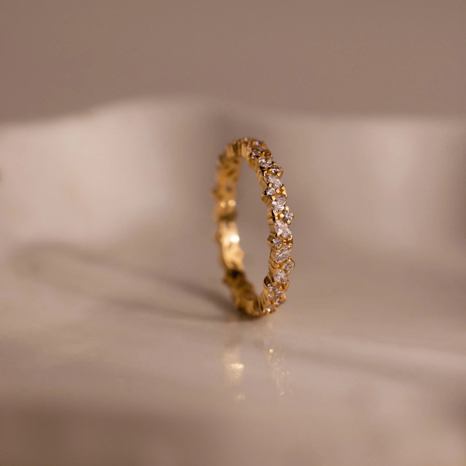 Gold ring with small diamonds on a beige background