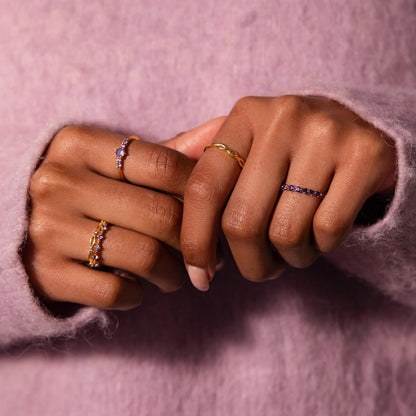 Close-up of two hands wearing rings on a pink background
