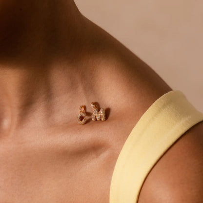 Close-up of a person wearing gold earrings with a neutral background