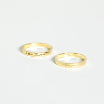 Two gold rings with engraved text on a white background