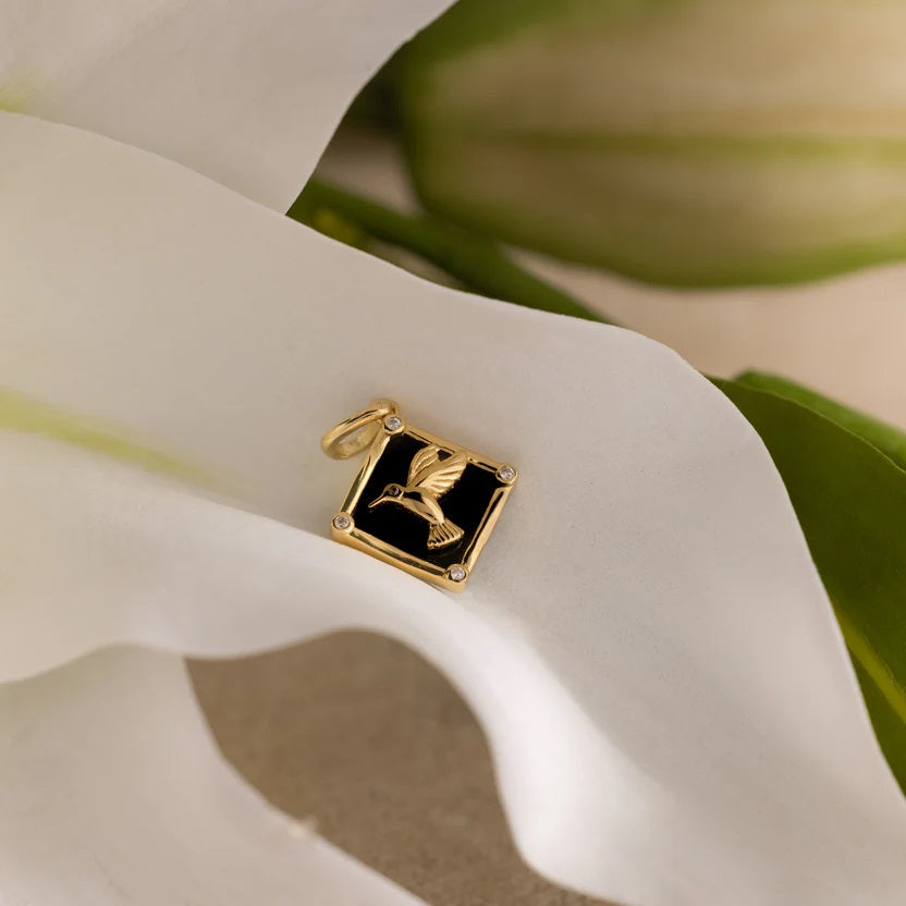 Gold and black pendant on a white flower