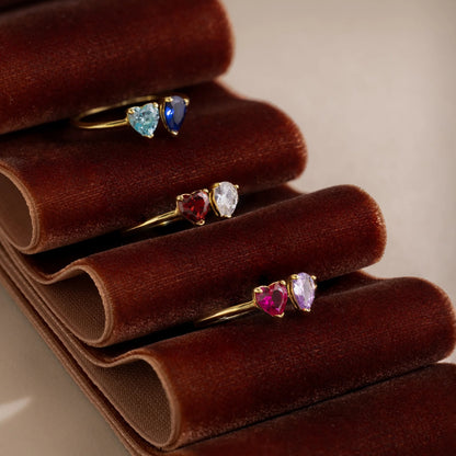 Set of heart-shaped gemstone rings on a brown velvet stand