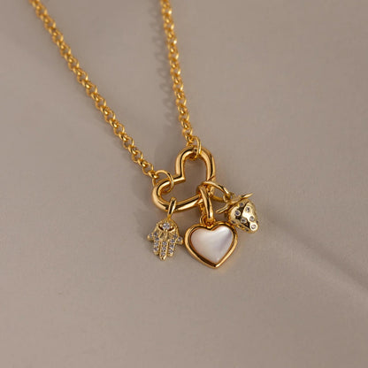 Gold necklace with heart-shaped pendant and other charms on a beige background
