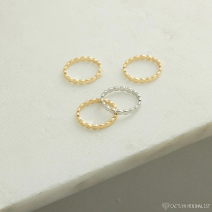 Three gold and silver rings on a light gray surface with 'Caitlyn Minimalist' branding.