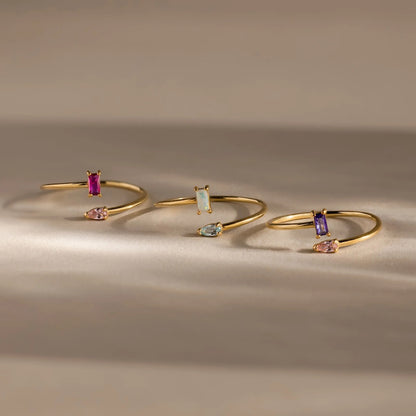 Three gold bangle bracelets with gemstones on a neutral background