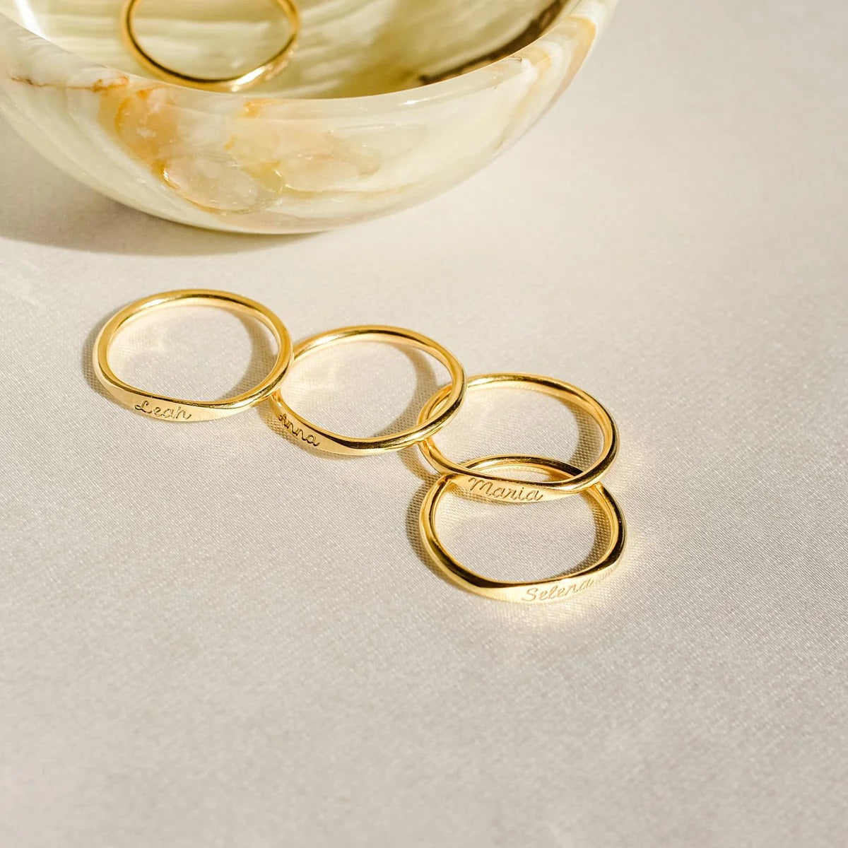 Set of gold rings with engraved names on a light background