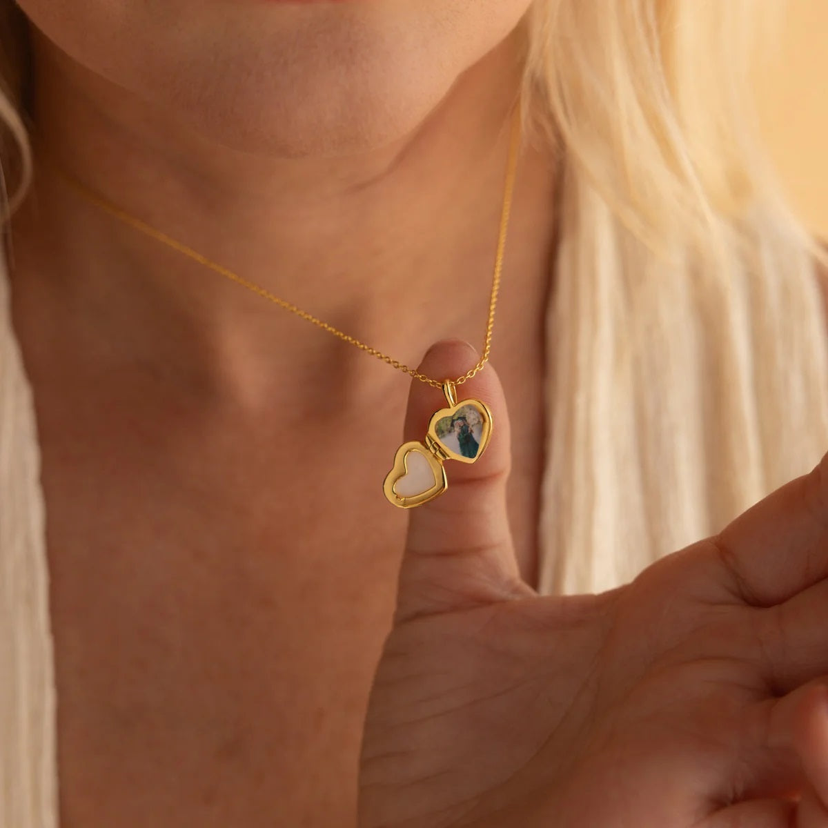 Gold necklace with a heart-shaped locket worn by a person